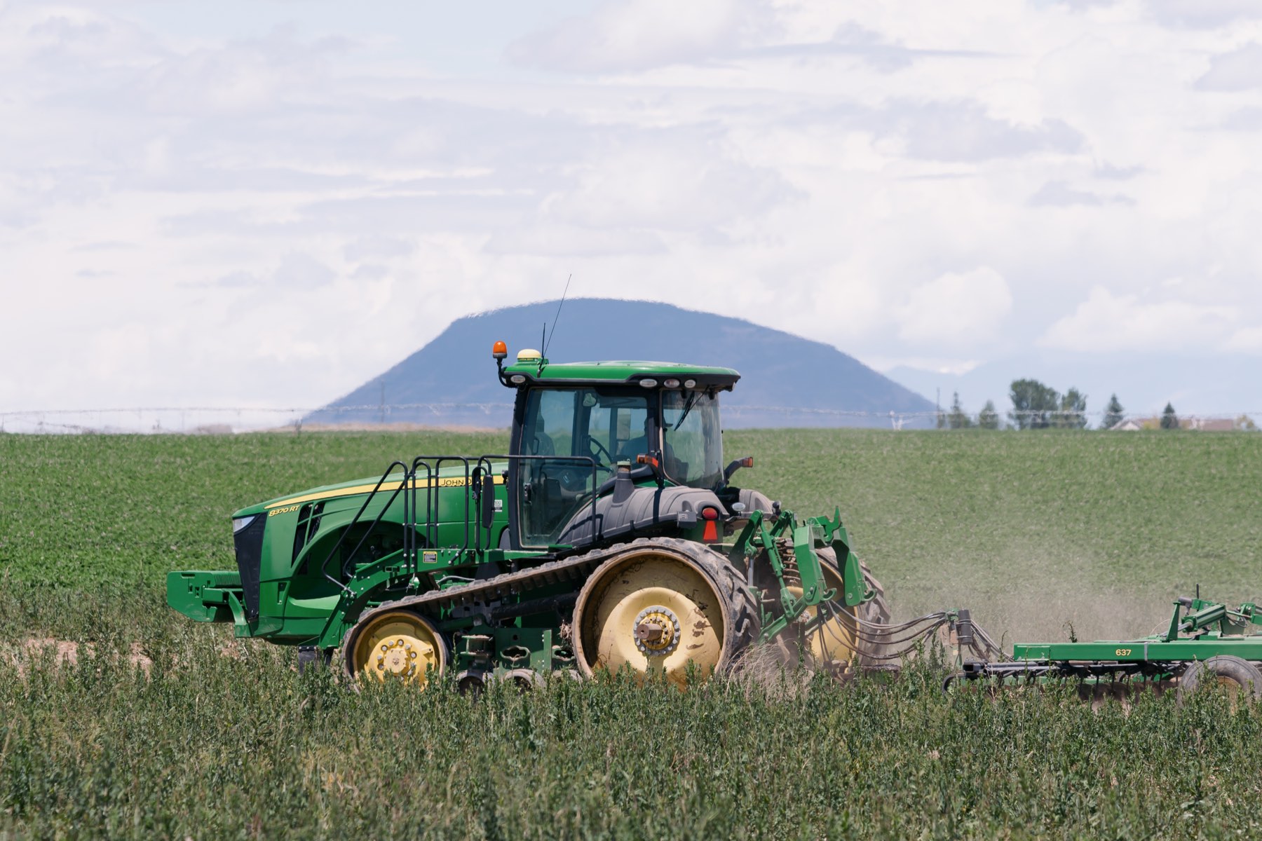A Benson Farms tractor working a potato field with a mountain backdrop